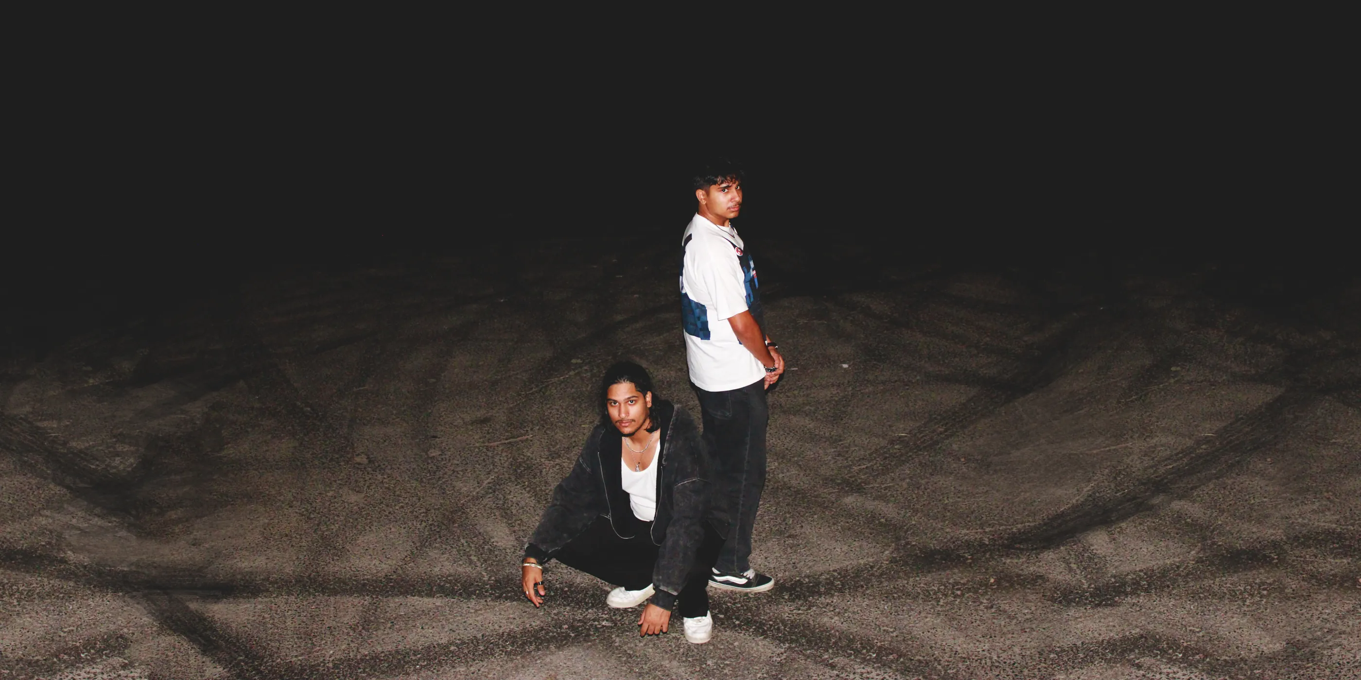 The two Moderni builders in an empty parking lot at night, lit by camera flash