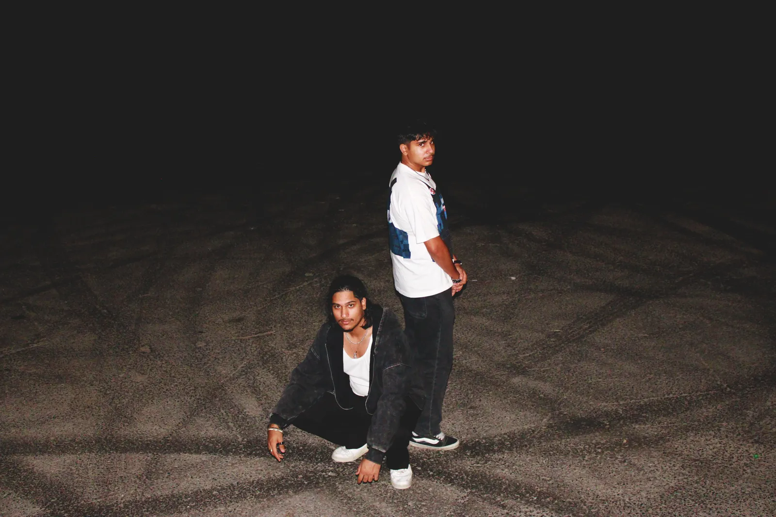 The two Moderni builders in an empty lot at night, lit by camera flash
